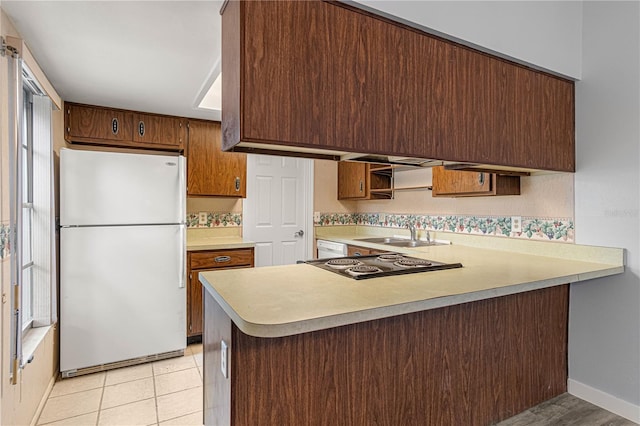 kitchen with white appliances, tasteful backsplash, a peninsula, light countertops, and a sink