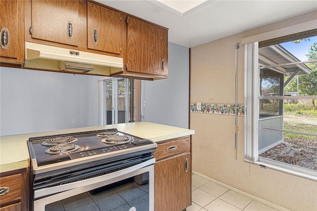 kitchen featuring light countertops, stainless steel electric range, brown cabinets, and under cabinet range hood