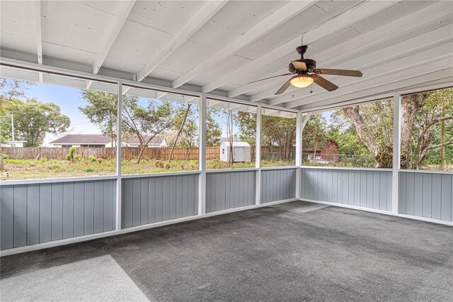 unfurnished sunroom with ceiling fan and beam ceiling