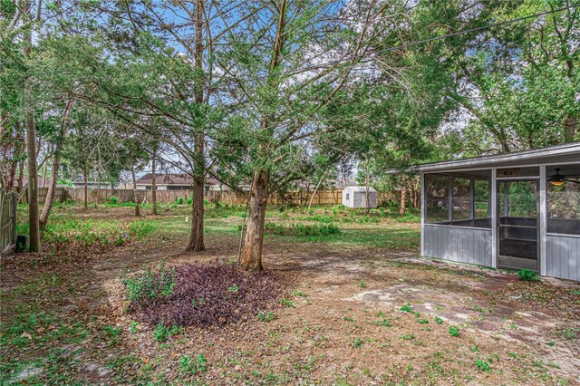 view of yard featuring a sunroom, a storage shed, fence, and an outbuilding