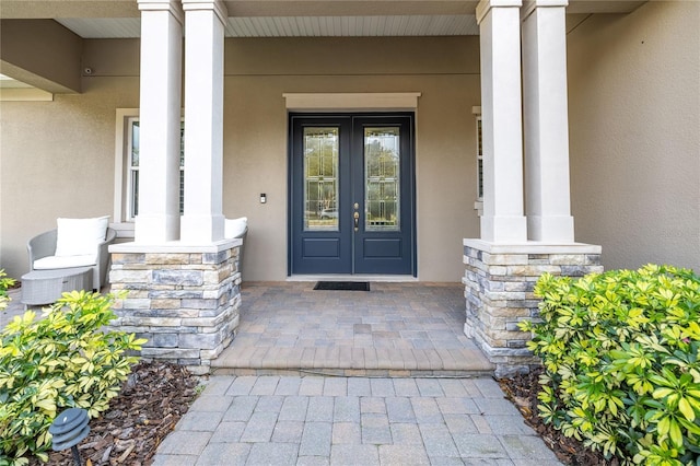 property entrance featuring covered porch, stone siding, and stucco siding