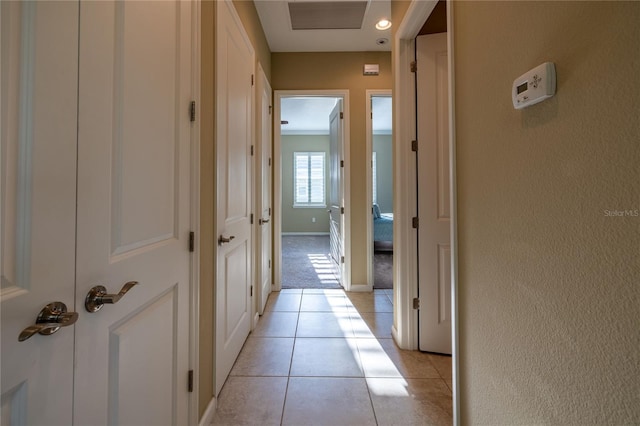 hallway with light tile patterned floors, visible vents, and baseboards