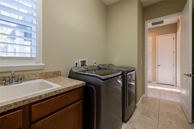 laundry room with laundry area, visible vents, washing machine and clothes dryer, a sink, and light tile patterned flooring