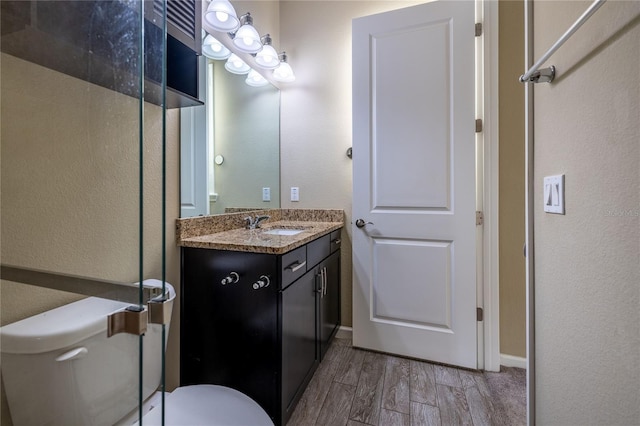 bathroom with baseboards, a textured wall, toilet, wood finished floors, and vanity