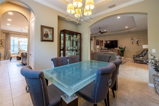 dining space with arched walkways, light tile patterned flooring, ceiling fan with notable chandelier, visible vents, and a tray ceiling