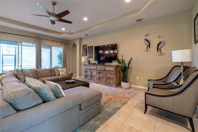 tiled living area featuring visible vents, arched walkways, baseboards, a tray ceiling, and recessed lighting