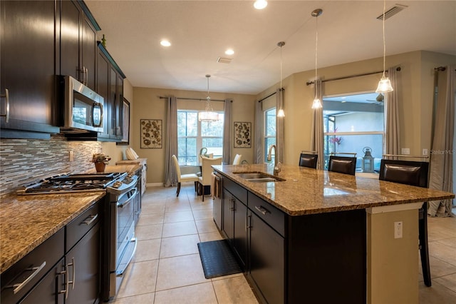 kitchen with light tile patterned floors, visible vents, appliances with stainless steel finishes, a sink, and a kitchen bar