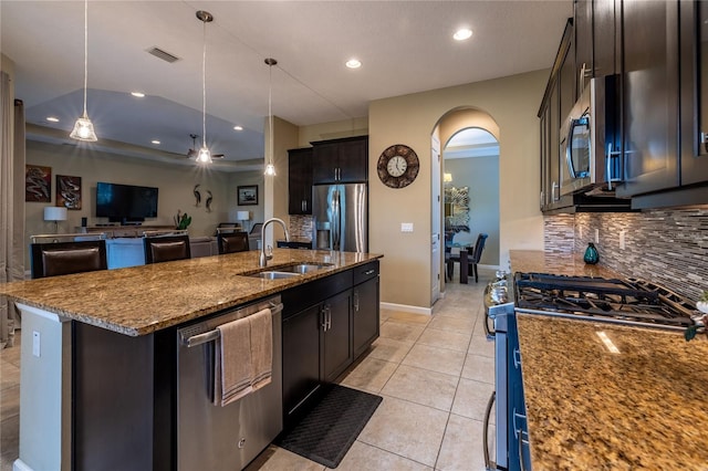 kitchen featuring arched walkways, visible vents, dark stone counters, stainless steel appliances, and a sink