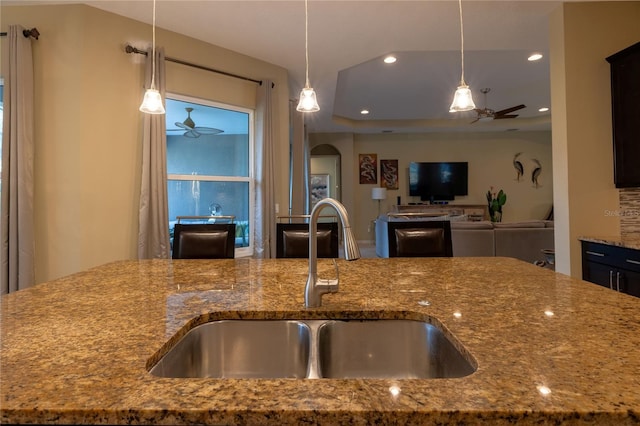 kitchen featuring ceiling fan, stone counters, recessed lighting, a sink, and decorative light fixtures