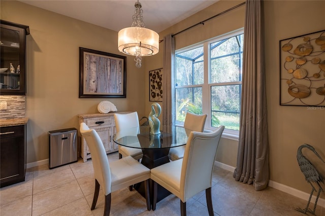 dining space featuring light tile patterned floors, a notable chandelier, and baseboards