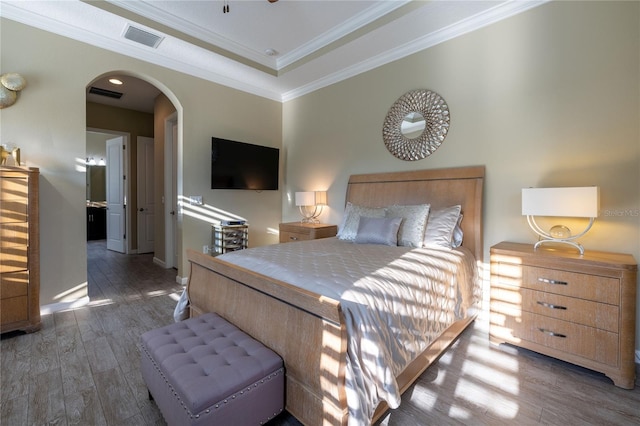 bedroom with ornamental molding, arched walkways, visible vents, and wood finished floors