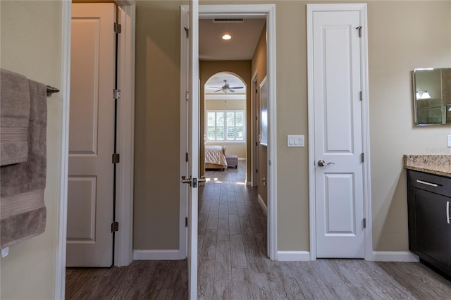 ensuite bathroom with visible vents, ensuite bathroom, vanity, wood finished floors, and baseboards