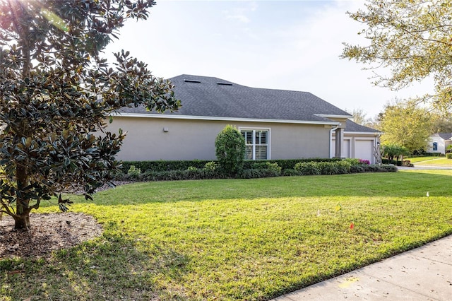 view of side of property featuring roof with shingles, a yard, an attached garage, and stucco siding