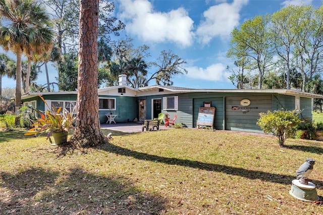 rear view of property with a chimney, a lawn, and a patio area