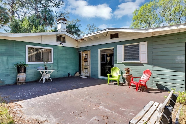 exterior space featuring driveway, a patio, and a chimney