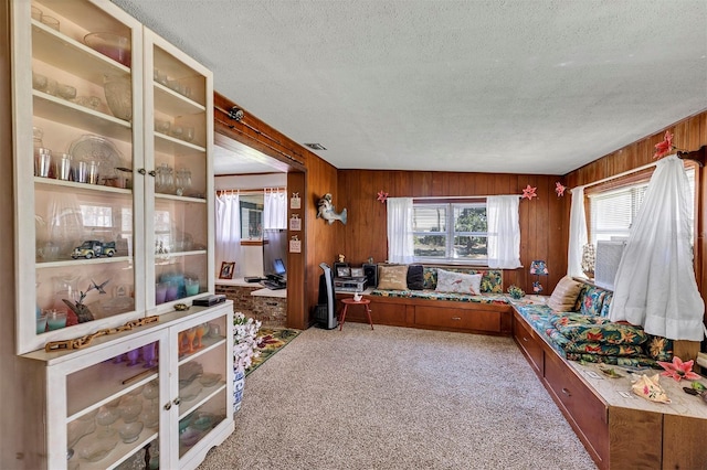 home office featuring carpet, wooden walls, visible vents, and a textured ceiling