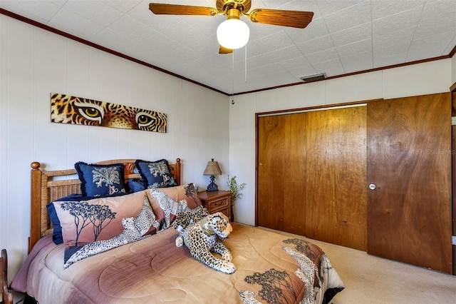 carpeted bedroom with visible vents, a closet, ornamental molding, and a ceiling fan