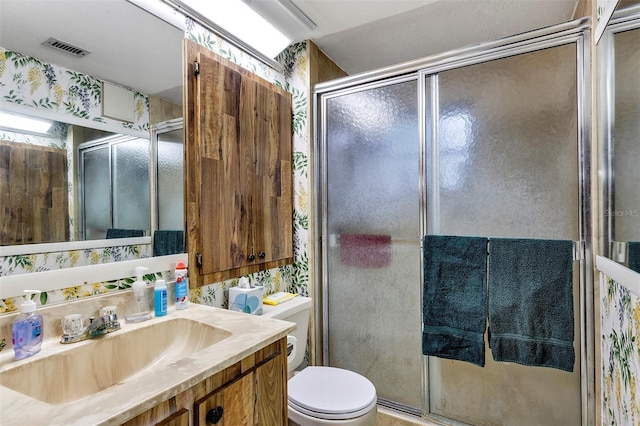 full bath with visible vents, vanity, a shower stall, and toilet