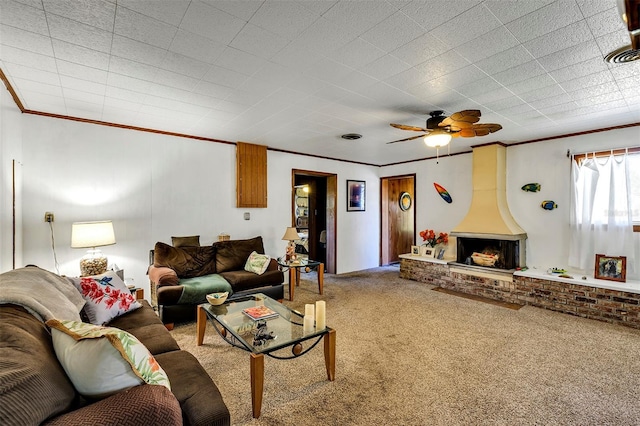 carpeted living area featuring ornamental molding, a large fireplace, and a ceiling fan