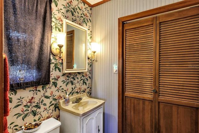 bathroom featuring toilet, wallpapered walls, a closet, and vanity