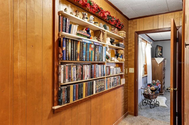 hallway featuring wood walls, carpet, and ornamental molding