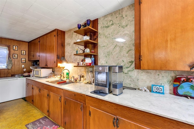 kitchen featuring brown cabinetry, light countertops, a sink, and white microwave