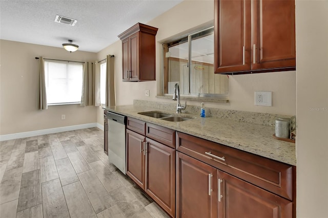 kitchen with visible vents, light stone countertops, a textured ceiling, stainless steel dishwasher, and a sink