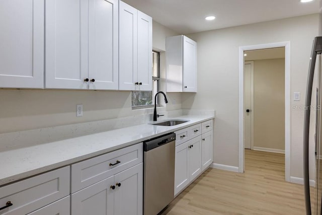 kitchen with light stone counters, stainless steel dishwasher, white cabinetry, a sink, and light wood-type flooring