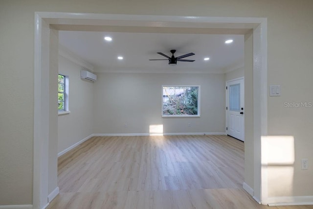 spare room featuring baseboards, an AC wall unit, light wood-style flooring, and crown molding