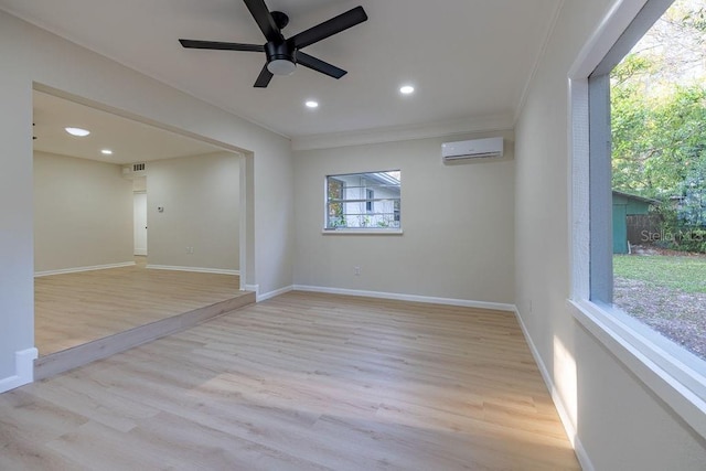 empty room with baseboards, a wall unit AC, visible vents, and light wood finished floors