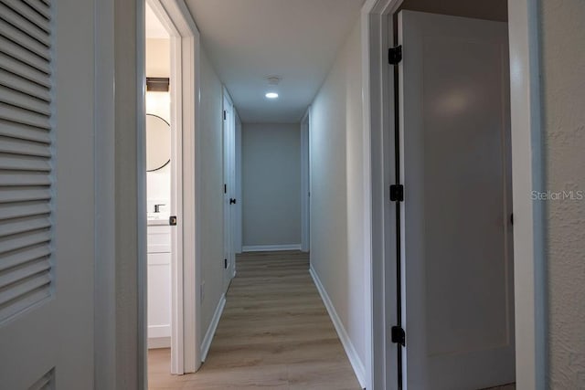 hallway featuring light wood-style floors and baseboards