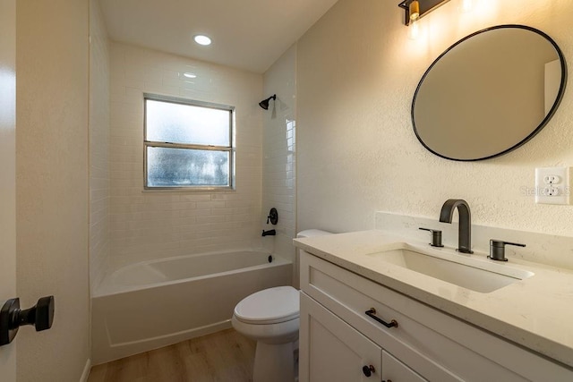 bathroom featuring shower / bathtub combination, a textured wall, toilet, wood finished floors, and vanity