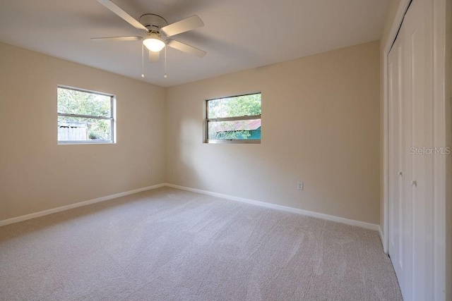 spare room featuring baseboards, a ceiling fan, and light colored carpet