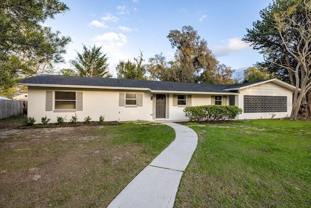 ranch-style home featuring fence and a front lawn