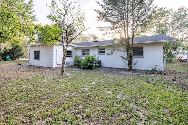 rear view of property featuring a yard and fence