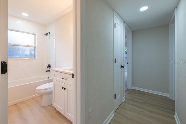 full bathroom featuring toilet, washtub / shower combination, vanity, wood finished floors, and baseboards