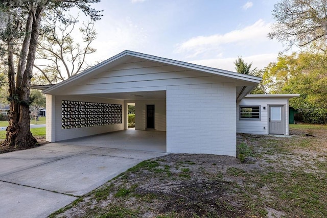 exterior space featuring concrete driveway, brick siding, and an attached carport