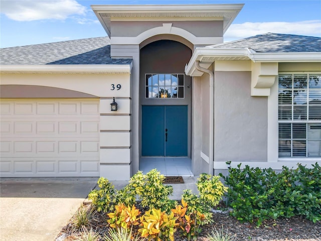 doorway to property with a garage, stucco siding, driveway, and roof with shingles