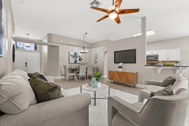 living area featuring light tile patterned floors, ceiling fan with notable chandelier, visible vents, and baseboards