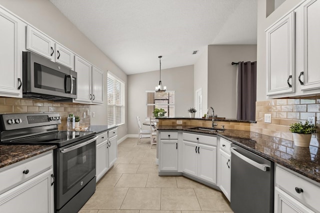 kitchen featuring light tile patterned floors, white cabinets, appliances with stainless steel finishes, a peninsula, and a sink