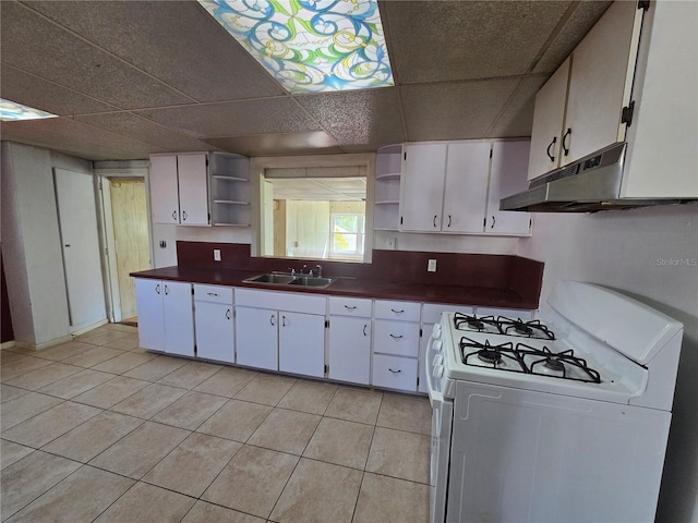 kitchen with dark countertops, open shelves, white gas range oven, and white cabinetry