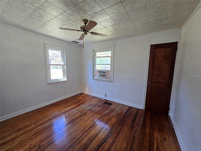 empty room with dark wood-style floors, cooling unit, baseboards, and a ceiling fan