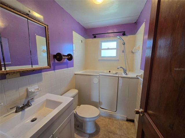 full bathroom featuring toilet, bathing tub / shower combination, vanity, tile walls, and tile patterned floors