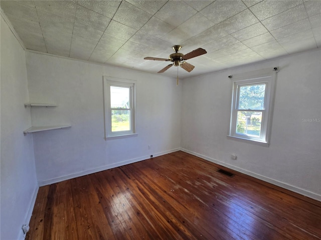 spare room featuring a ceiling fan, visible vents, baseboards, and hardwood / wood-style flooring