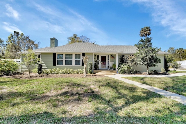 ranch-style home featuring a shingled roof, a chimney, and a front yard