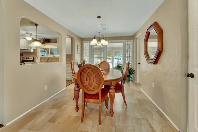 dining area featuring baseboards, a chandelier, arched walkways, and a healthy amount of sunlight