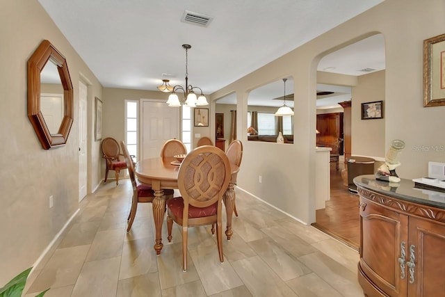 dining space featuring a notable chandelier, visible vents, and baseboards