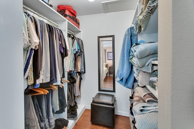 walk in closet with attic access and wood finished floors