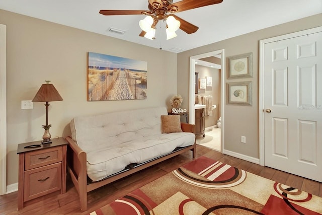 living area with a ceiling fan, baseboards, visible vents, and wood finished floors