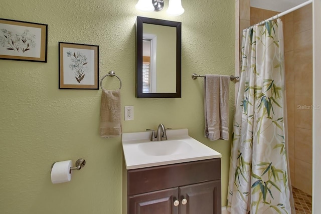 full bath featuring a tile shower and vanity